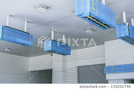 A scene of equipment at a closed gas station covered with blue tarpaulins for protection. 139202746