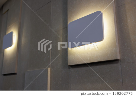 Modern illuminated wall lamp on textured interior wall in office conference space Modern illuminated wall lamp on textured interior wall in office conference space 139202775