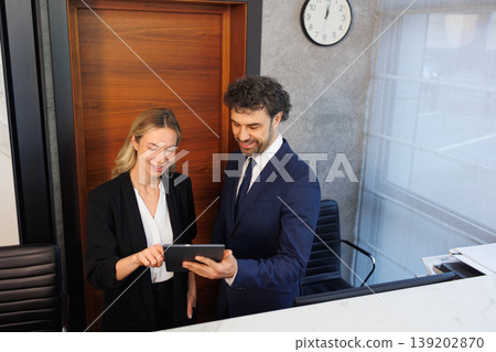 Professional hotel reception staff using digital tablet at modern front desk 139202870
