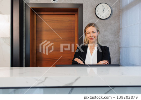 Confident female receptionist standing at modern hotel front desk portrait Confident female receptionist standing at modern hotel front desk portrait 139202879