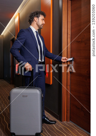Elegant Business Traveler Unlocking Hotel Room Door With Suitcase In Modern Corridor 139203060