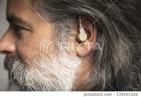 Hearing aid in the ear of a middle-aged man Hearing aid in the ear of a middle-aged man 139203108