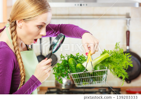 Woman looking through magnifier at vegetables basket 139203333
