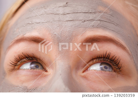 Closeup of woman having grey mud mask on face Closeup of woman having grey mud mask on face 139203359