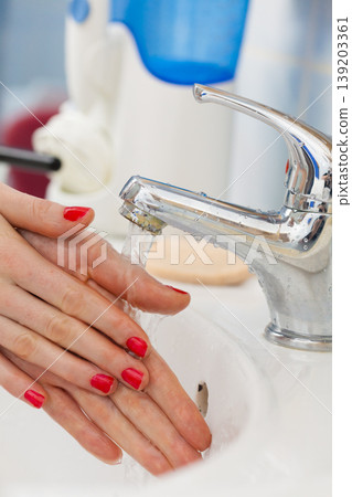 Woman washing hands under flowing tap water in the bathroom Woman washing hands under flowing tap water in the bathroom 139203361