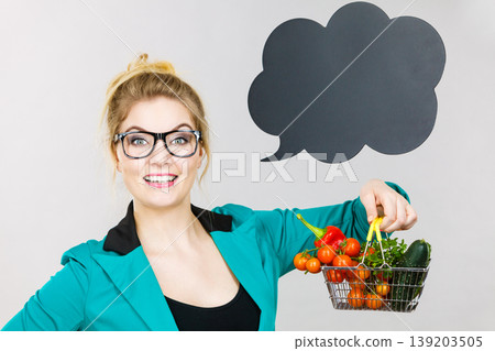 Woman holds shopping cart with vegetables, copy space Woman holds shopping cart with vegetables, copy space 139203505