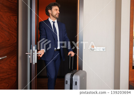 Professional Businessman Entering Hotel Suite With Rolling Luggage Professional Businessman Entering Hotel Suite With Rolling Luggage 139203694