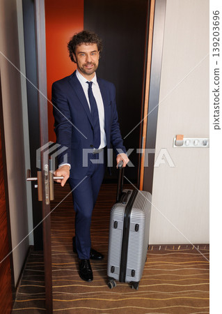Corporate Traveler Entering Modern Hotel Room With Carry On Suitcase Corporate Traveler Entering Modern Hotel Room With Carry On Suitcase 139203696