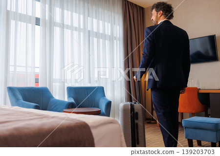 Rear View Of Businessman In Hotel Room With Suitcase Rear View Of Businessman In Hotel Room With Suitcase 139203703