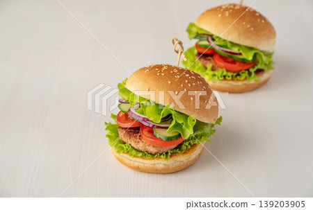A homemade burger with beef, tomato, cheese, and lettuce on a white background. A homemade burger with beef, tomato, cheese, and lettuce on a white background. 139203905