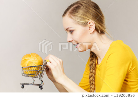 Woman holding shopping cart with bread Woman holding shopping cart with bread 139203956