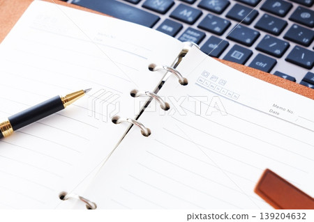 某人在筆記型電腦上進行辦公桌工作的圖片,其中環形筆記本打開。 某人在筆記型電腦上進行辦公桌工作的圖片,其中環形筆記本打開。 139204632