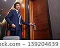 Confident Business Man Entering Hotel Room Using Key Card And Carrying Luggage 139204639