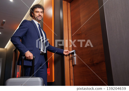 Confident Business Man Entering Hotel Room Using Key Card And Carrying Luggage 139204639