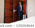 Smiling Business Traveler Opening Hotel Room Door With Suitcase After Check In 139204644