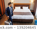 Businessman arriving to hotel room with suitcase and looking at comfortable bed 139204645