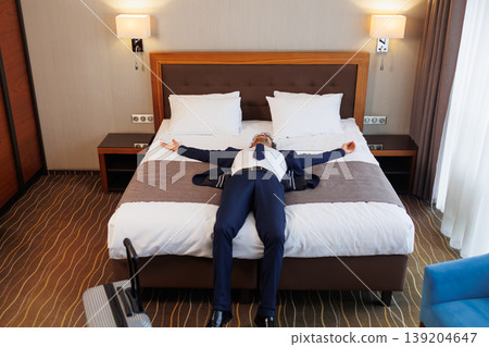 Business traveler lying on hotel bed relaxing after successful trip and long journey Business traveler lying on hotel bed relaxing after successful trip and long journey 139204647