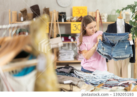 Teenage girl choosing jean shorts in clothing store 139205193
