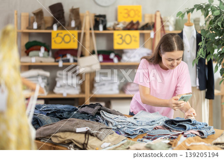 Teen girl scans qr code jeans in clothing store Teen girl scans qr code jeans in clothing store 139205194