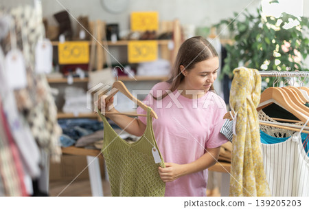 Teenage girl choosing top in clothing store Teenage girl choosing top in clothing store 139205203
