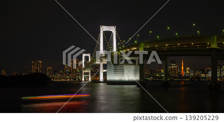 A panoramic night view featuring the illuminated Rainbow Bridge, the trails of light from houseboats across the water, and Tokyo Tower in the distance. A panoramic night view featuring the illuminated Rainbow Bridge, the trails of light from houseboats across the water, and Tokyo Tower in the distance. 139205229