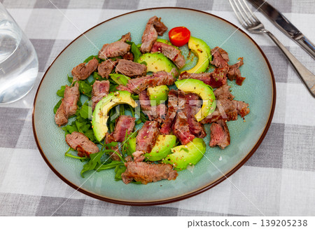 Grilled beef steak with seasonings, served with avocado, sesame seeds and parsley, tomatoes 139205238