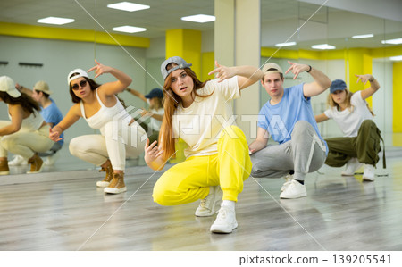 Teenage girls and boys having group dance training in studio, performing dynamic elements Teenage girls and boys having group dance training in studio, performing dynamic elements 139205541