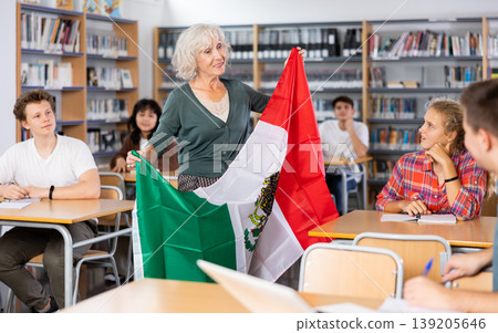 Mature female teacher shows scholchildren the national flag of Mexico Mature female teacher shows scholchildren the national flag of Mexico 139205646