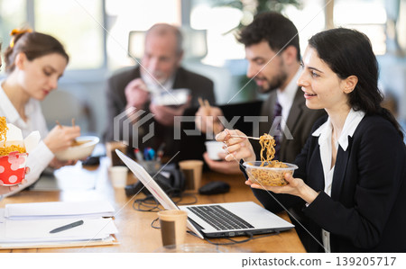 Lunch break - woman eating noodles with colleagues in modern office Lunch break - woman eating noodles with colleagues in modern office 139205717