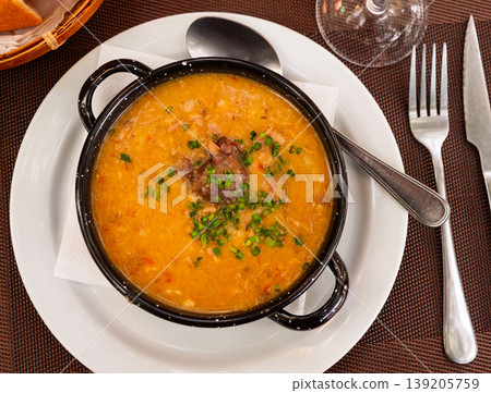 There is traditional Spanish dish on table - Fabada Asturian decorated with chopped green onions There is traditional Spanish dish on table - Fabada Asturian decorated with chopped green onions 139205759