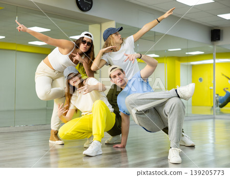 Teenage girls and a boy performing breakdance poses in dance hall Teenage girls and a boy performing breakdance poses in dance hall 139205773