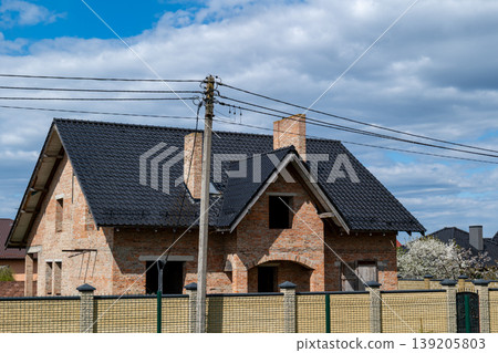 New house displays metal tiles on the roof with a brick exterior in a suburban setting on a sunny day New house displays metal tiles on the roof with a brick exterior in a suburban setting on a sunny day 139205803