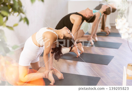 Young people doing camel yoga pose. 139205823