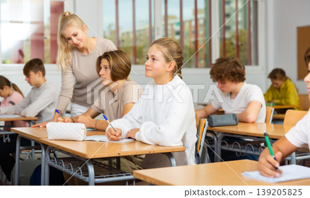 Teenagers sitting at desks in classroom during lesson Teenagers sitting at desks in classroom during lesson 139205825