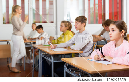 Teenagers sitting at desks in classroom during lesson Teenagers sitting at desks in classroom during lesson 139205859