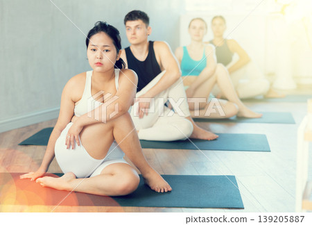 Focused Asian young girl performs Lord of Fishes asana by Ardha Matsyendrasana 139205887