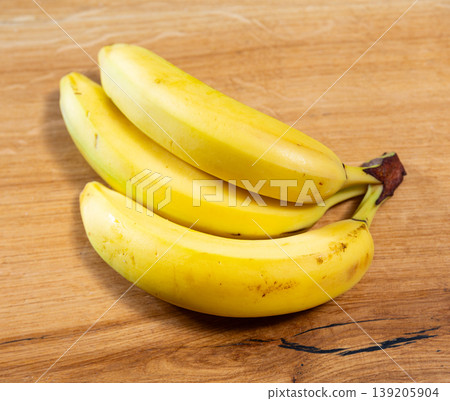 Three ripe bananas lie on wooden surface 139205904