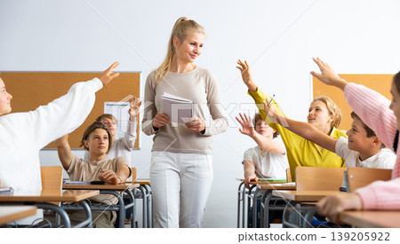Pupils raising hands during lesson in school Pupils raising hands during lesson in school 139205922