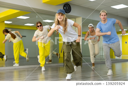 Group of teenagers in casual clothes training hip hop in class, posing and having fun Group of teenagers in casual clothes training hip hop in class, posing and having fun 139205924