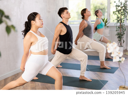 Young people doing a warrior yoga pose. Young people doing a warrior yoga pose. 139205945