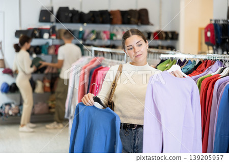 Young woman choosing sweatshirt in store Young woman choosing sweatshirt in store 139205957