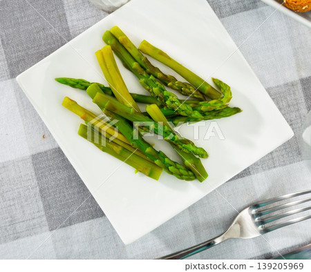 Fresh green asparagus with sunflower oil on white plate 139205969