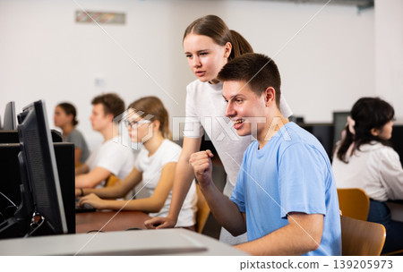 Smiling teenagers using computer during computer science lesson Smiling teenagers using computer during computer science lesson 139205973