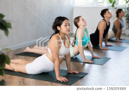 Group of young people doing an upward dog yoga pose. Group of young people doing an upward dog yoga pose. 139205989