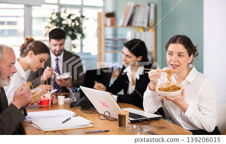 Young female companys employees eat instant noodles, lunch time during break for staff Young female companys employees eat instant noodles, lunch time during break for staff 139206015