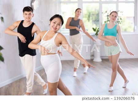 Positive young woman practicing dance positions during workout session 139206076