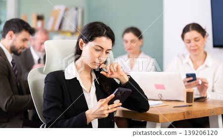 Girl scrolls feed and passes time on social media. Bored staff on smartphone in background 139206120