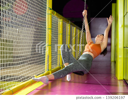 Woman enjoying riding zip line in colorful indoor amusement center 139206197