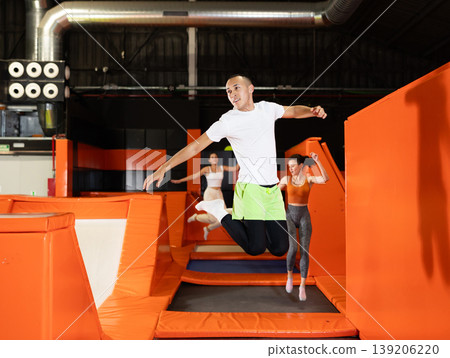 Male athlete training to jump on trampolines at trampoline center Male athlete training to jump on trampolines at trampoline center 139206220