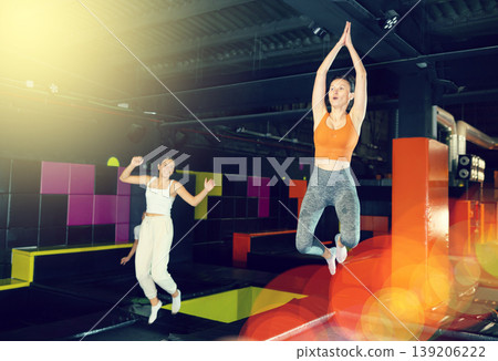 Excited woman enjoying jumping at well-equipped indoor trampoline arena Excited woman enjoying jumping at well-equipped indoor trampoline arena 139206222